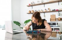 Diseñador gráfico femenino utilizando netbook y tableta con lápiz óptico mientras se trabaja en el proyecto en la mesa en el estudio creativo - foto de stock