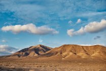 Weiße Wolken am strahlend blauen Himmel über trockenen Tälern und Hügeln an einem Sommertag auf Fuerteventura, Spanien — Stockfoto