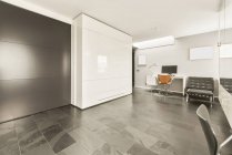 Interior de estilo loft minimalista de salón espacioso moderno con paredes blancas y suelos de mármol amueblado con sillones y decorado con pizarras en blanco - foto de stock