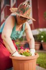Вид збоку на зрілу жінку садівника, переносить рослину до великого вазона в її домашньому саду — стокове фото