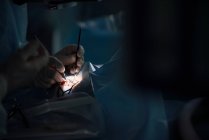 Cirurgião ocular anônimo de cultura com instrumentos manuais operando paciente na cama médica no hospital em fundo turvo — Fotografia de Stock