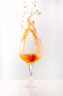 Cocktail orange rafraîchissant éclaboussant en verre brillant gobelet sur fond gris en studio — Photo de stock