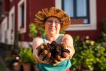 Mulher madura jardineiro mostrando novo solo para suas plantas em suas mãos — Fotografia de Stock