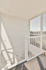 Fragment of interior design of modern apartment with white walls and stairway with railing and window in sunlight — Stock Photo