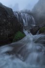 Захватывающий вид на водопады с чистыми аква-жидкостями на горе под туманным небом осенью — стоковое фото