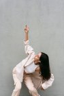 Dançarina feminina despreocupada ouvindo música em fones de ouvido e dançando com os olhos fechados enquanto desfruta de músicas no fundo da parede cinza na cidade — Fotografia de Stock