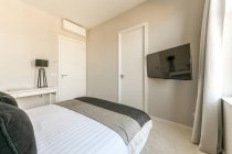 Interno di camera da letto contemporanea con letto con morbidi cuscini posizionati vicino alla finestra in appartamento in stile minimale — Foto stock