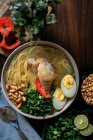 De cima de caldo de frango fresco apetitoso com ingredientes variados servidos em tigela na mesa na cozinha — Fotografia de Stock