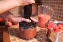 Обрізати анонімну домогосподарку, змішуючи помідори в блендері, готуючи соус маринари на кухні вдома — стокове фото