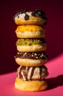 Tower of donuts of different colors and flavors on pink background — Stock Photo
