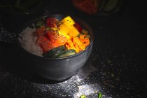 Hohe Winkel der asiatischen Poke mit Lachs und Reis mit verschiedenen Gemüse serviert in Schüssel auf dem Tisch im Restaurant — Stockfoto