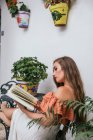 Side view of graceful female in skirt leaning legs on chair while chilling in patio in summer and enjoying interesting story in book at weekend — Stock Photo