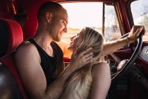 Loving couple looking at each other in vintage car parked in nature on sunny day — Stock Photo