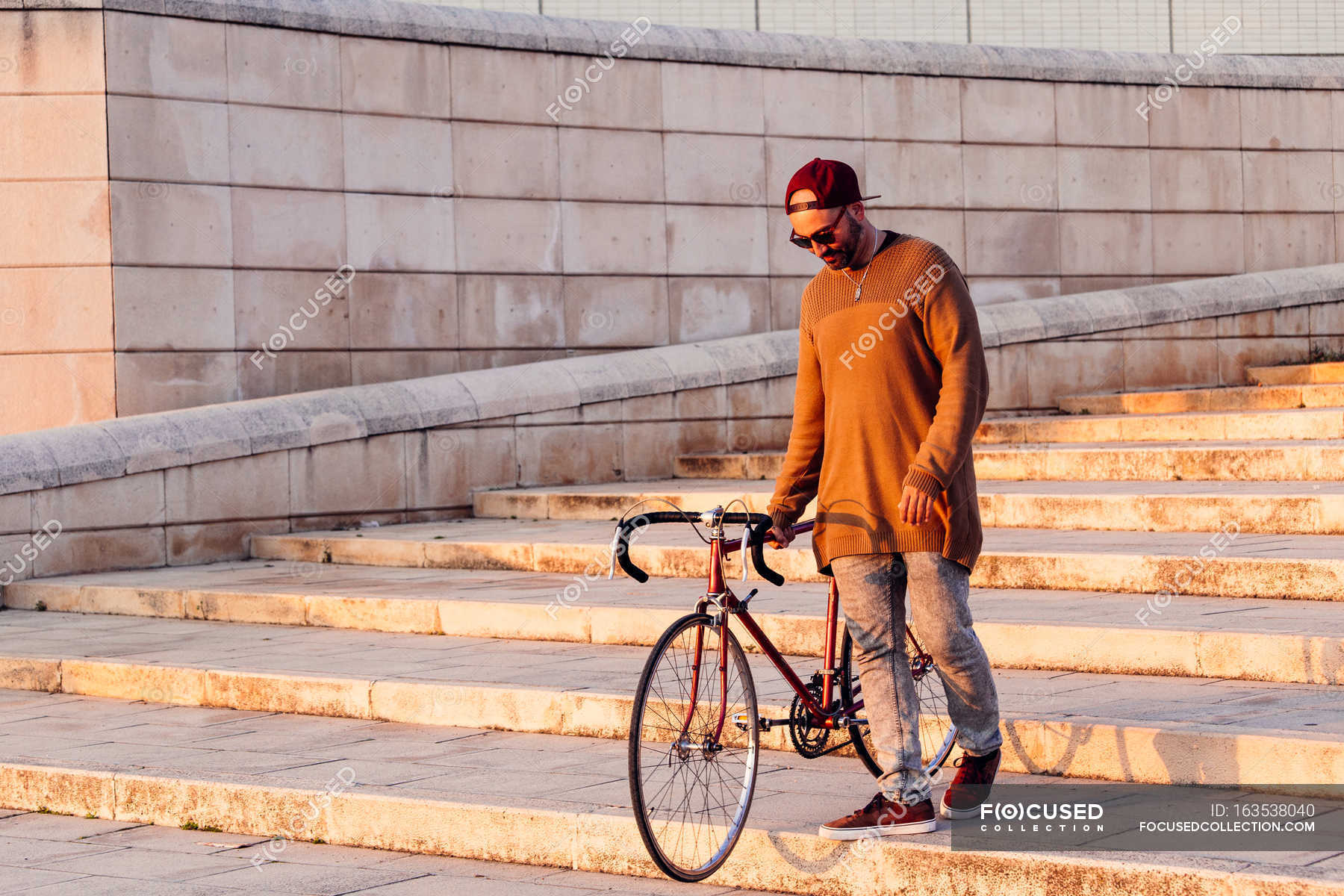 man-walking-down-stairs-with-bicycle-natural-light-light-stock