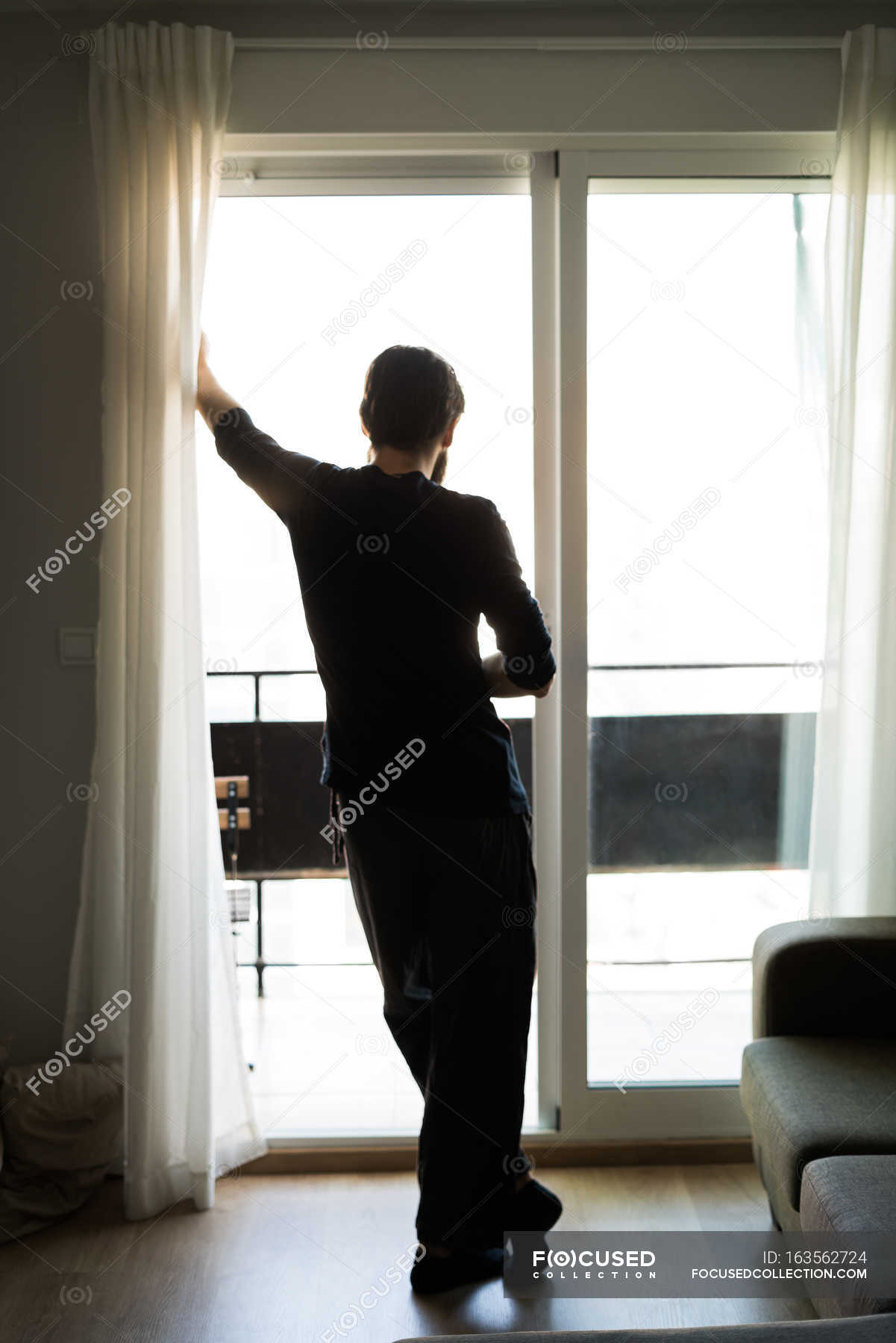 Premium Photo  Unrecognizable young man stands by the window