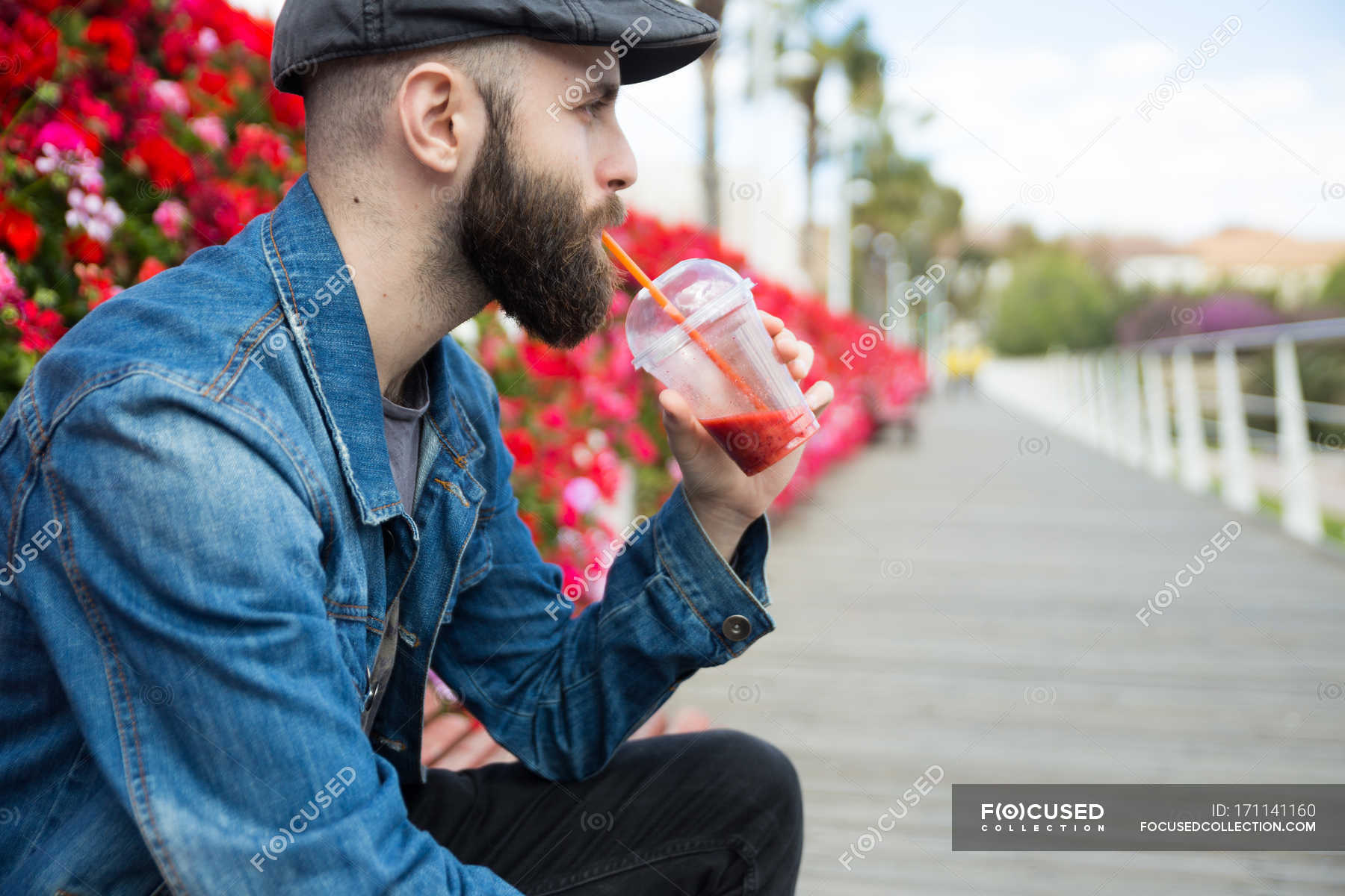 Side view of man drinking smoothie with straw and looking away. — beverage,  lifestyle - Stock Photo | #171141160