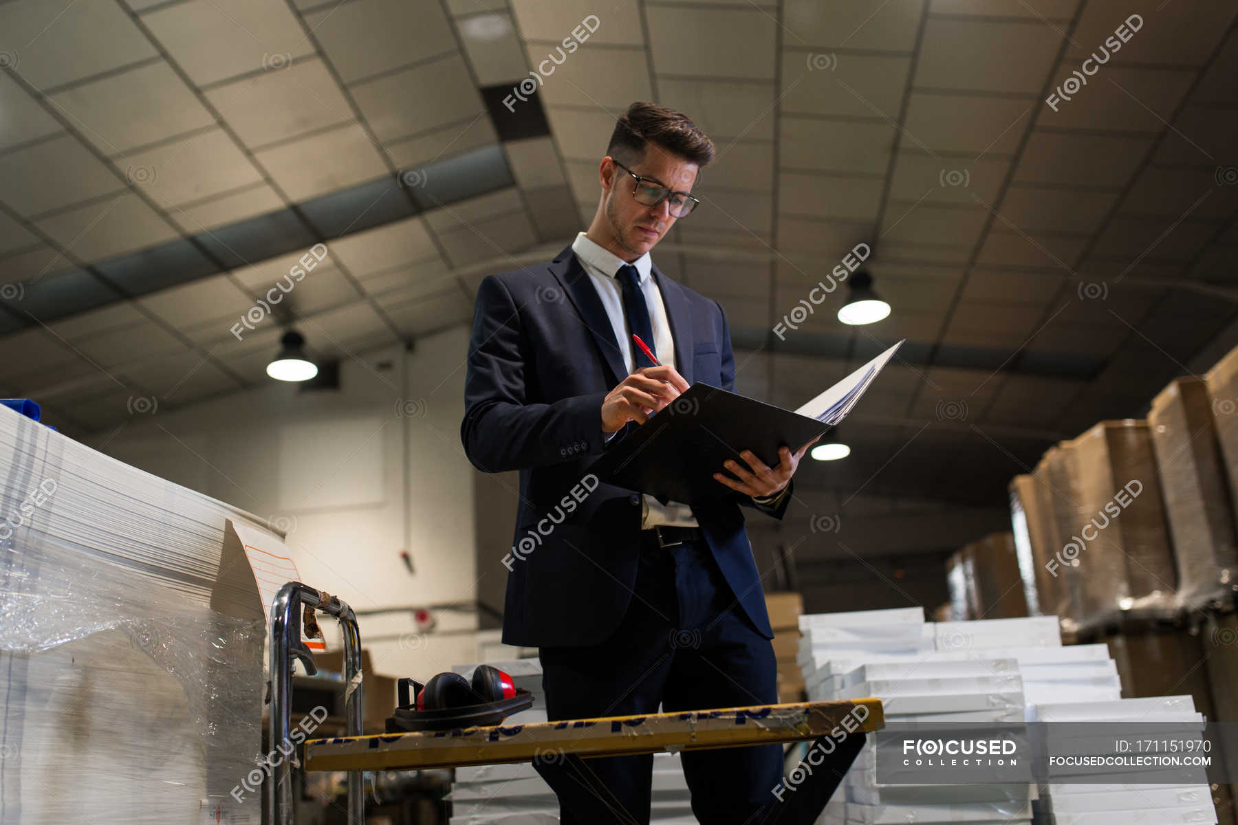 Serious man standing at table in workshop of factory and reading ...