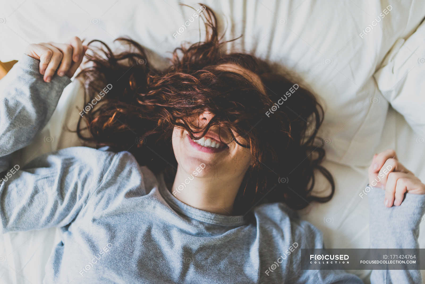 Девушка на кровати лежит прикрывает лицо