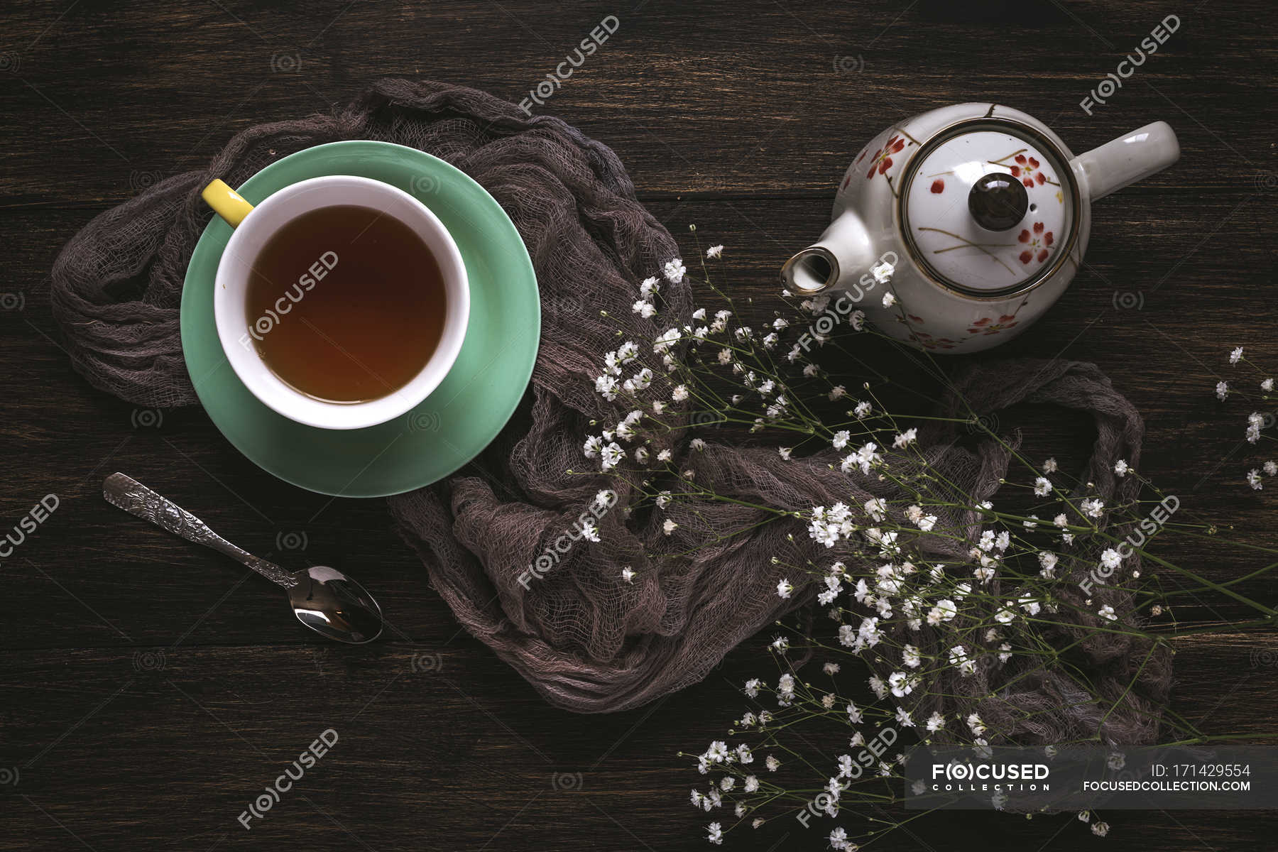 Cup of tea and teapot with wildflowers on brown surface — freshness ...