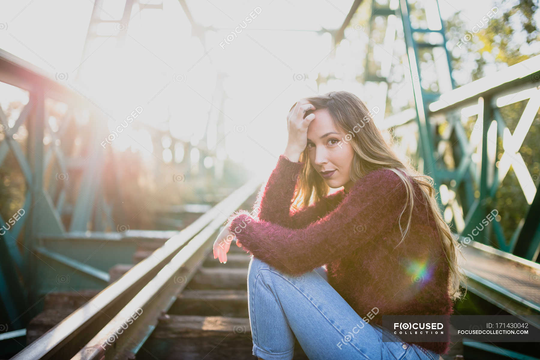 Girl sitting on rail and looking at camera. — rail sleeper, attractive ...