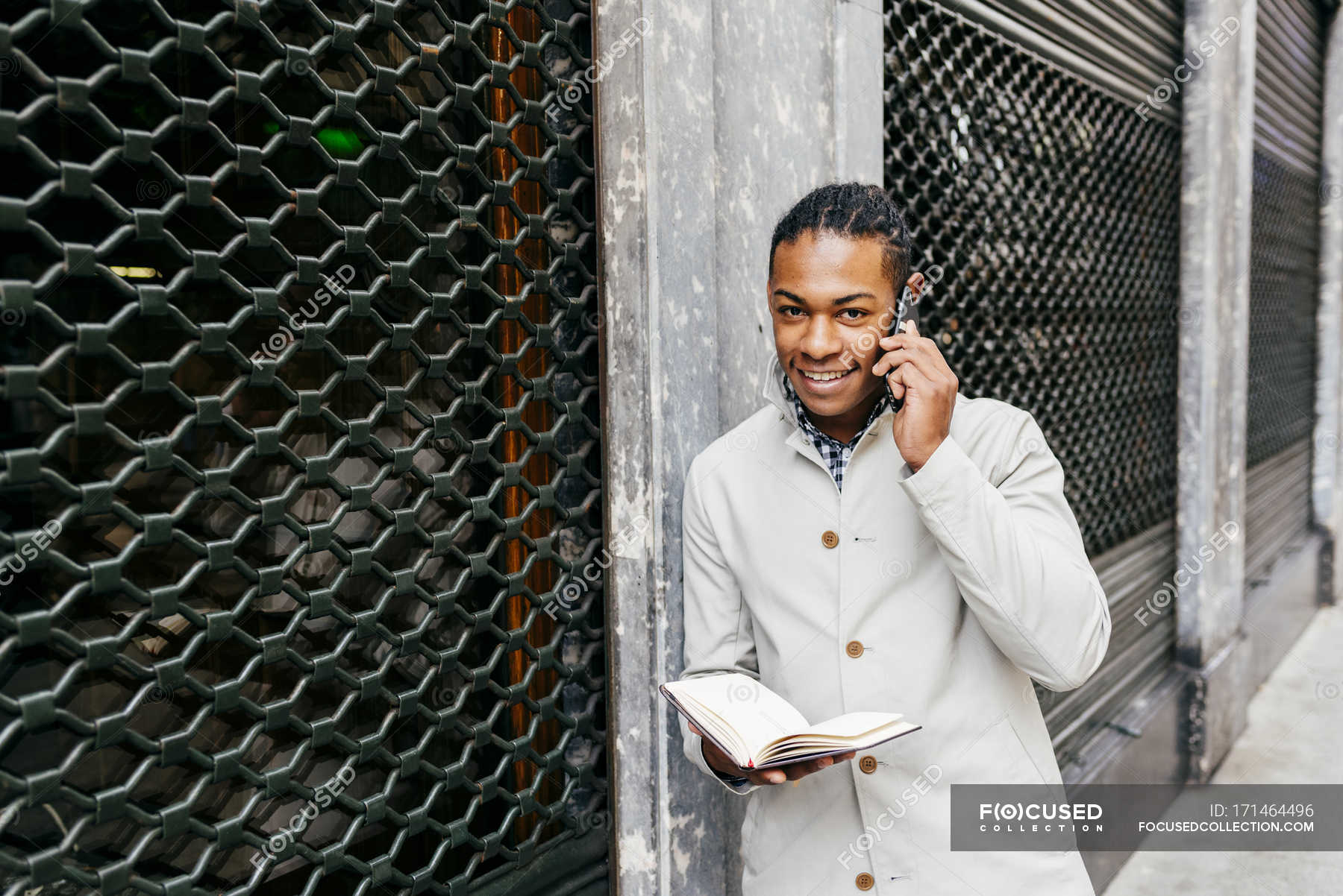 Man watching notebook and talking smartphone at street — confidence ...