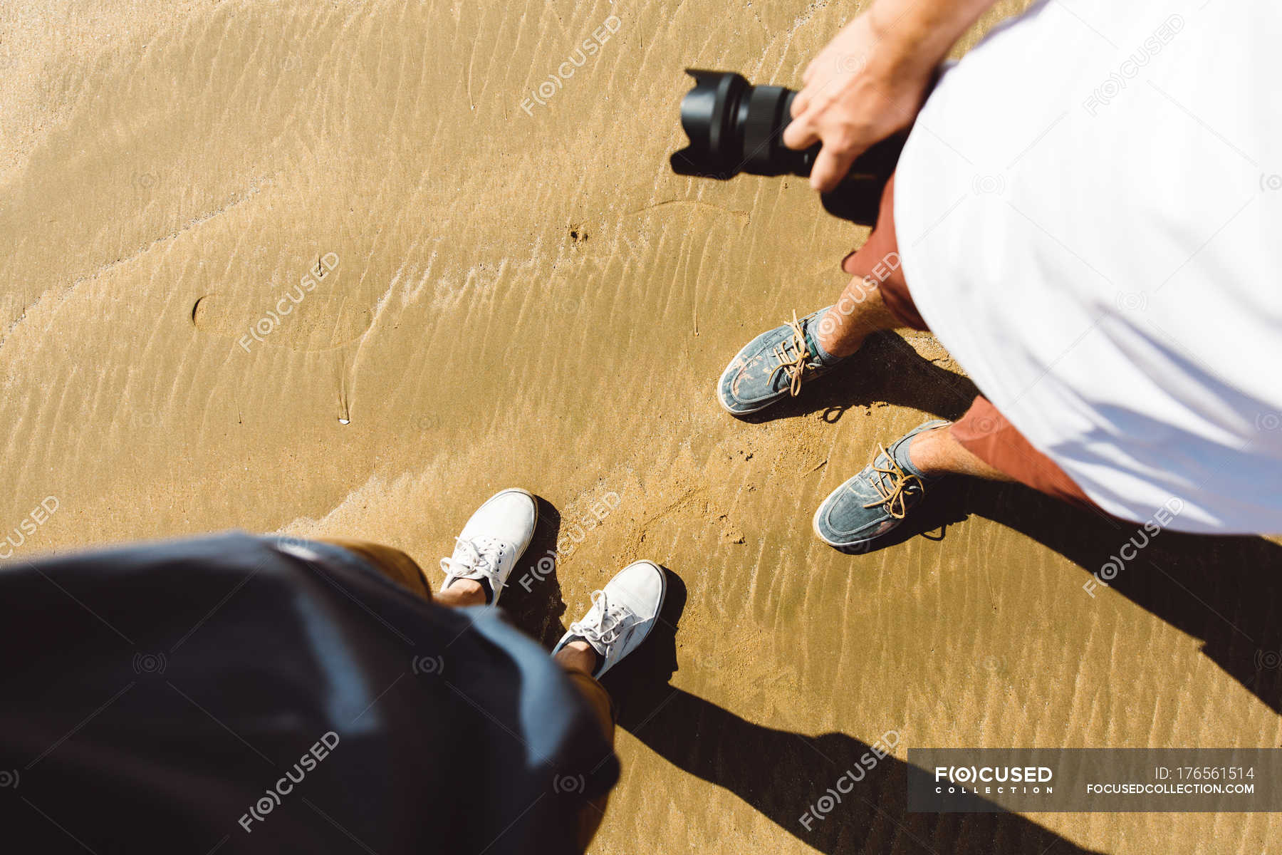 Looking Down View Of Two Persons Standing On Wet Sand With Looking Down View Of Two Persons Standing On Wet Sand With Stock Photos