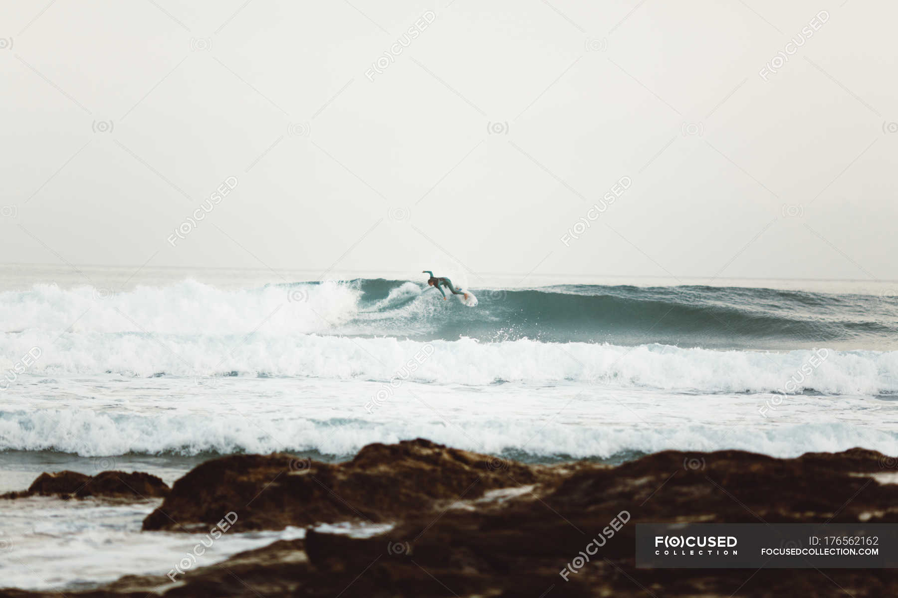 Side view of surfer catching waves at seashore — lifestyle, anonymous
