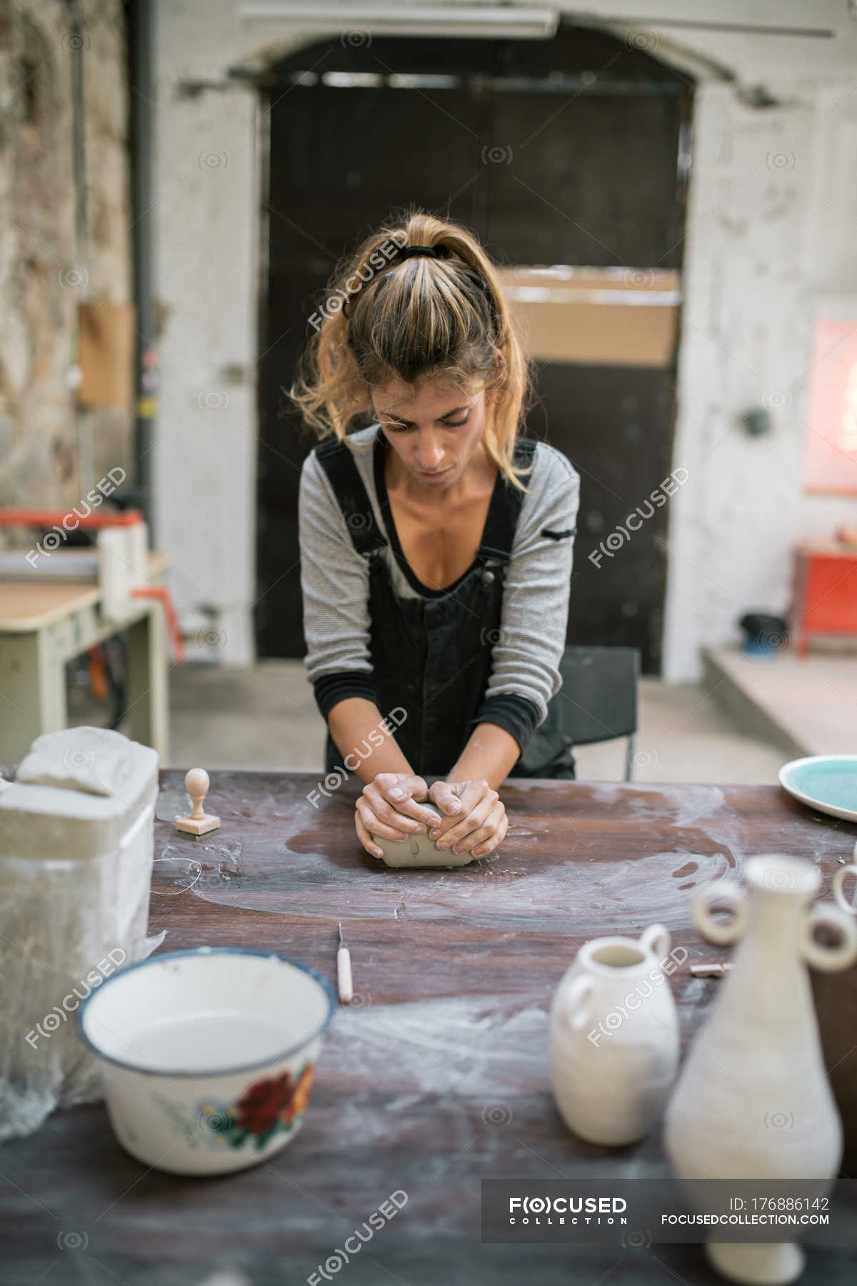 Front view of concentrated potter kneading clay on table at