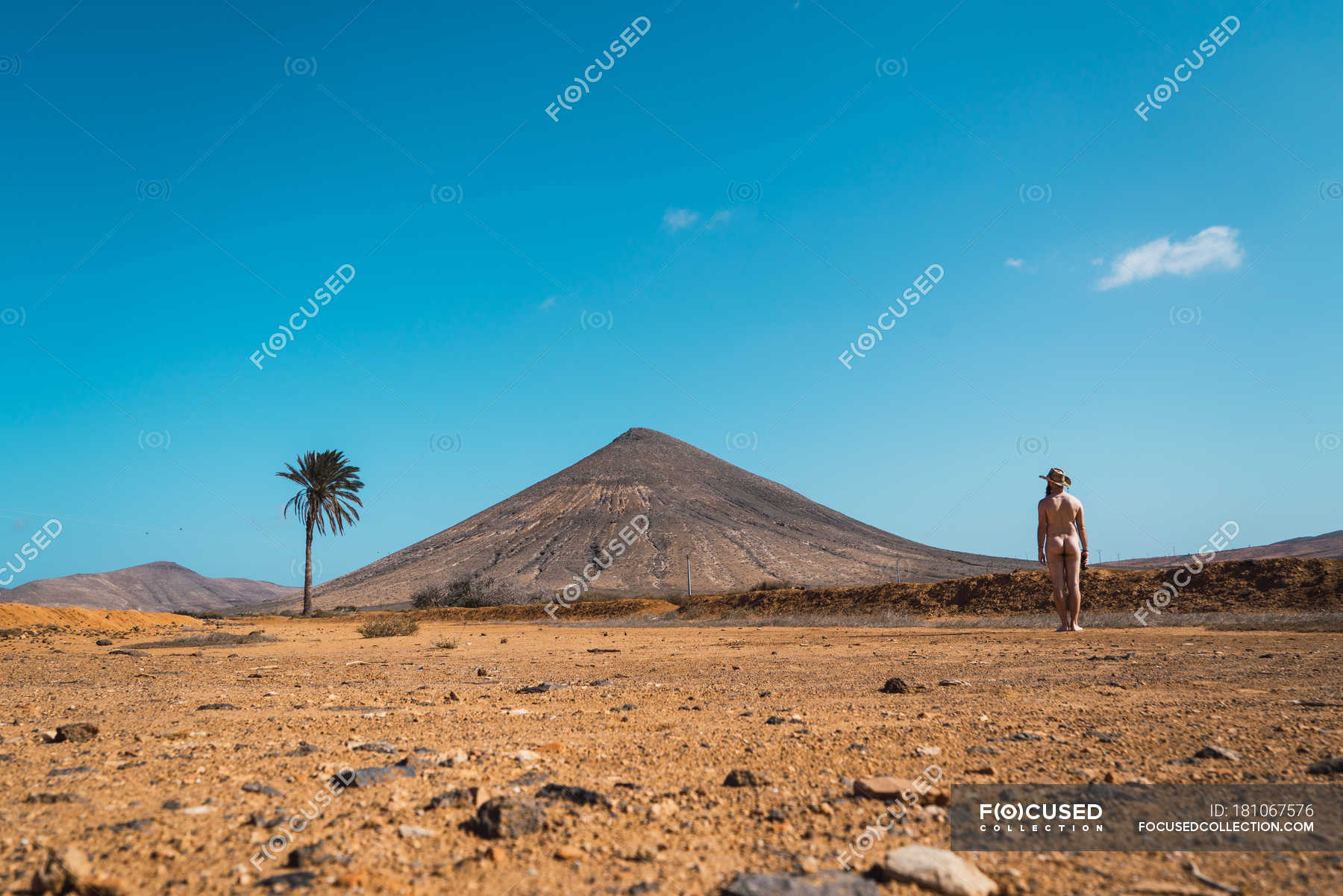 Vista trasera del hombre desnudo posando en el paisaje tropical del desierto exploración Seco