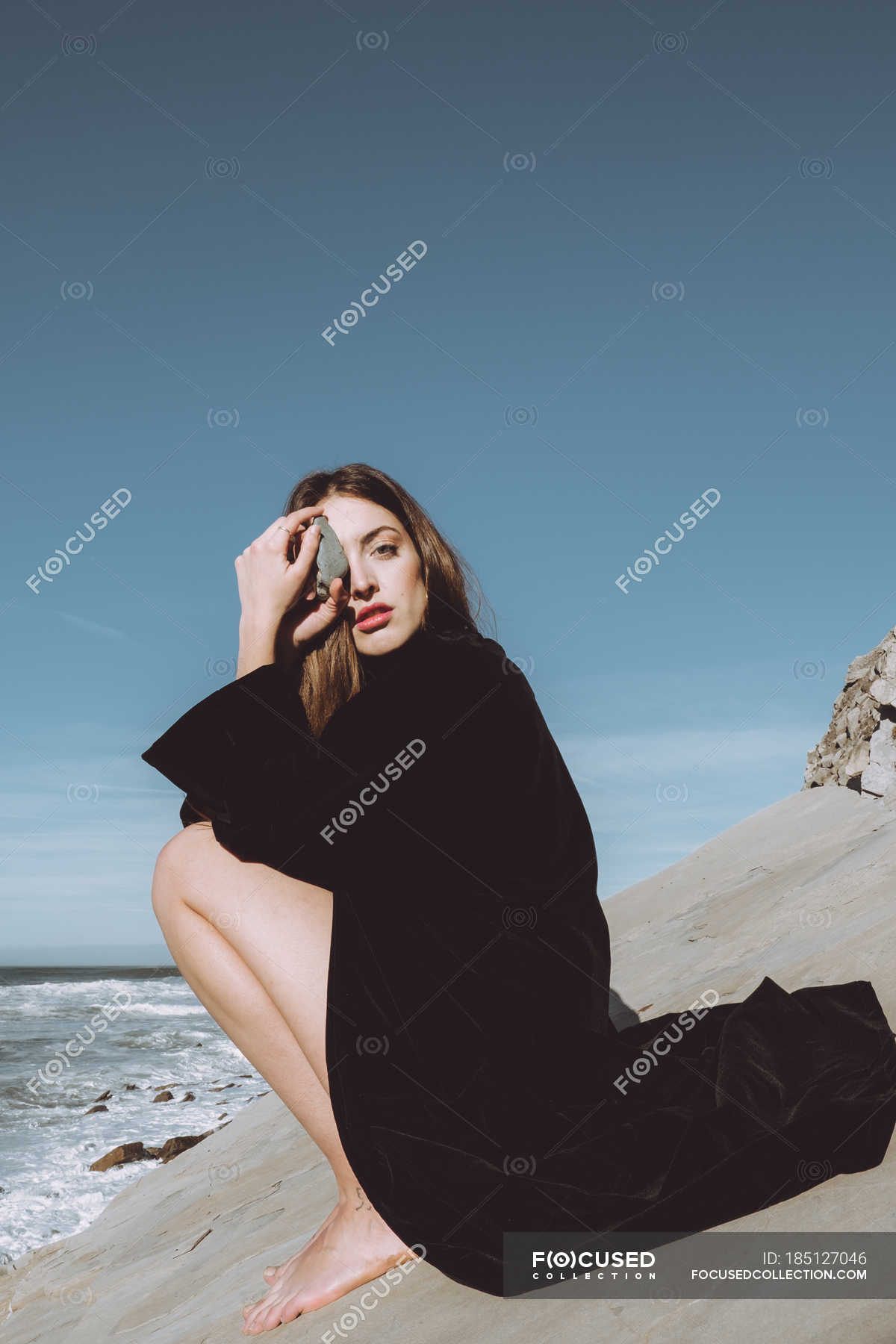 https://st.focusedcollection.com/9163412/i/1800/focused_185127046-stock-photo-brunette-black-coat-sitting-coastline.jpg