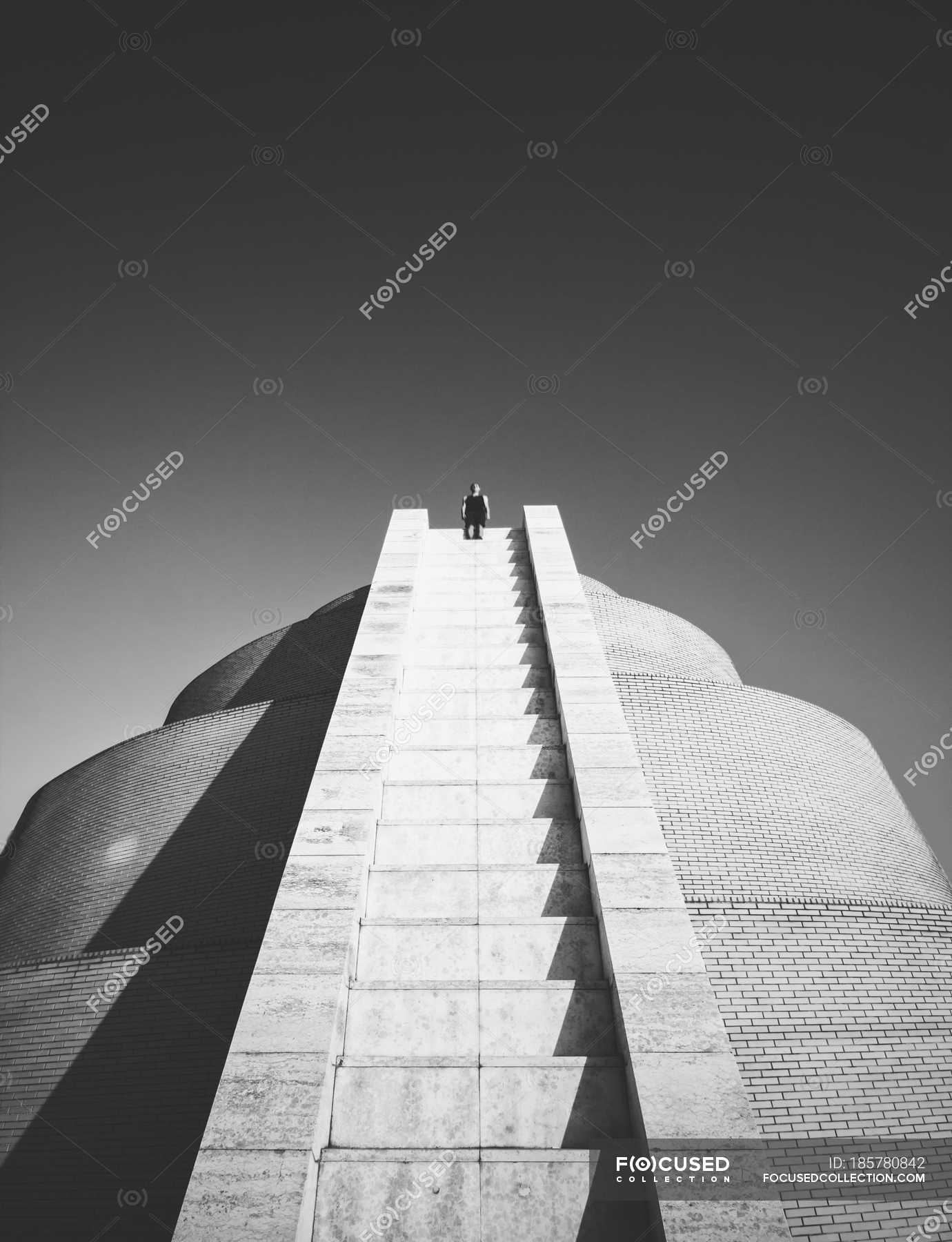 Man sitting on the top of brick uncommon building over sky — city ...