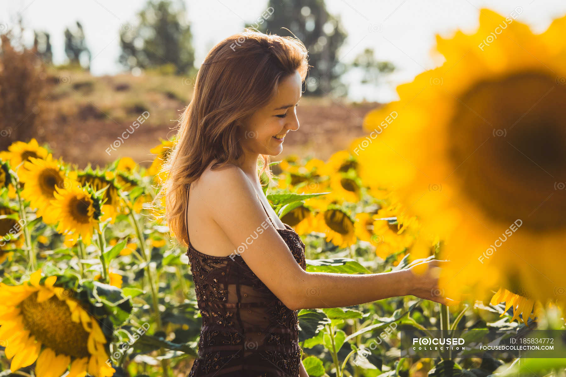 Vista lateral de mujer sonriente en girasoles — Zona rural, alegres - Stock  Photo | #185834772