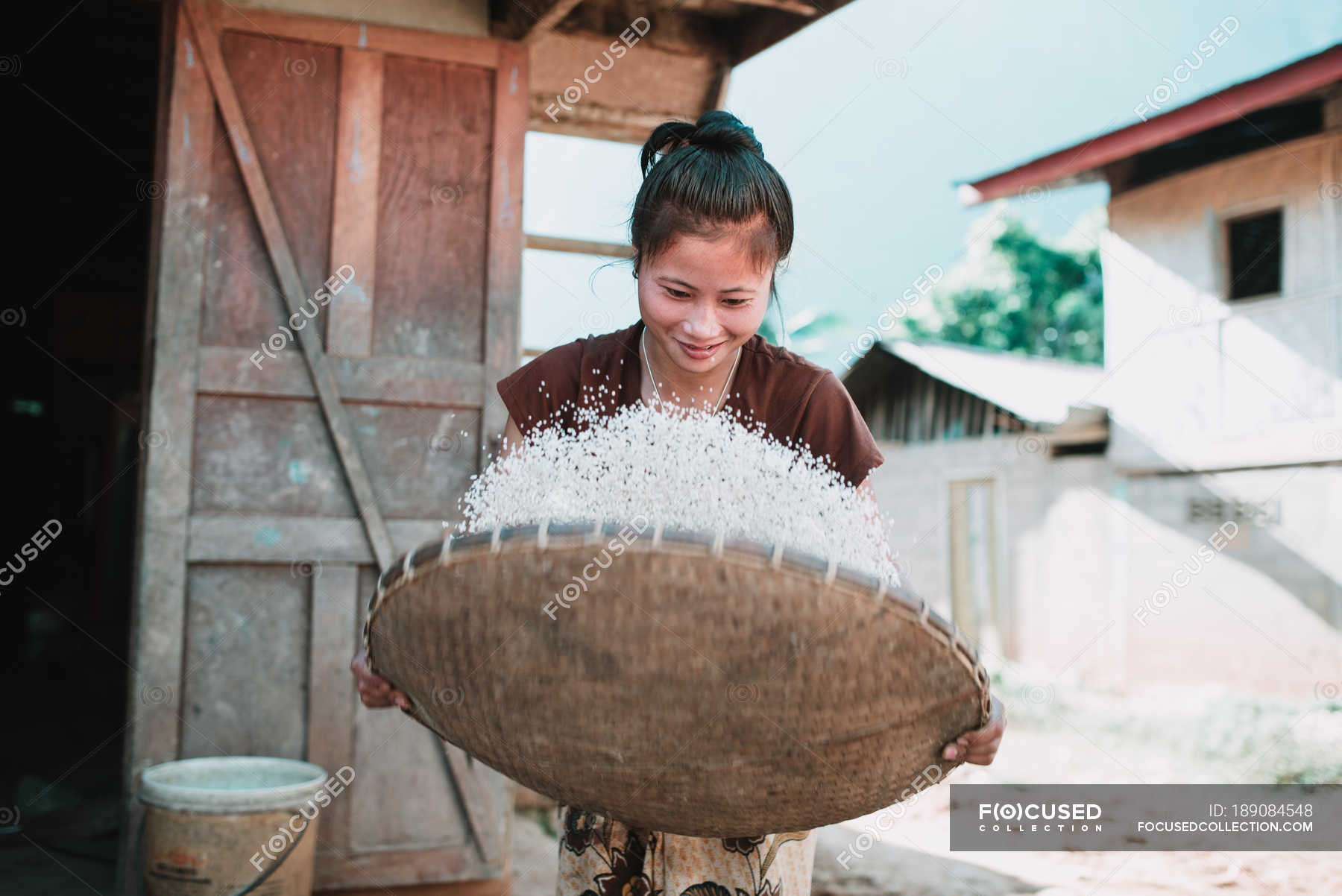 Nong Khiaw Laos Woman Winnowing Rice In Basket While Standing On Sunny Day — Rural Raw