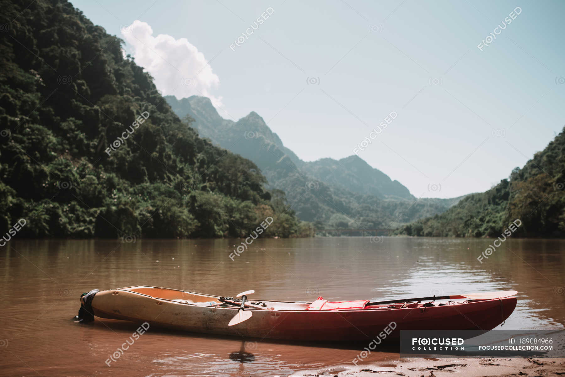 Wooden canoe standing at river shore running through mountains ...