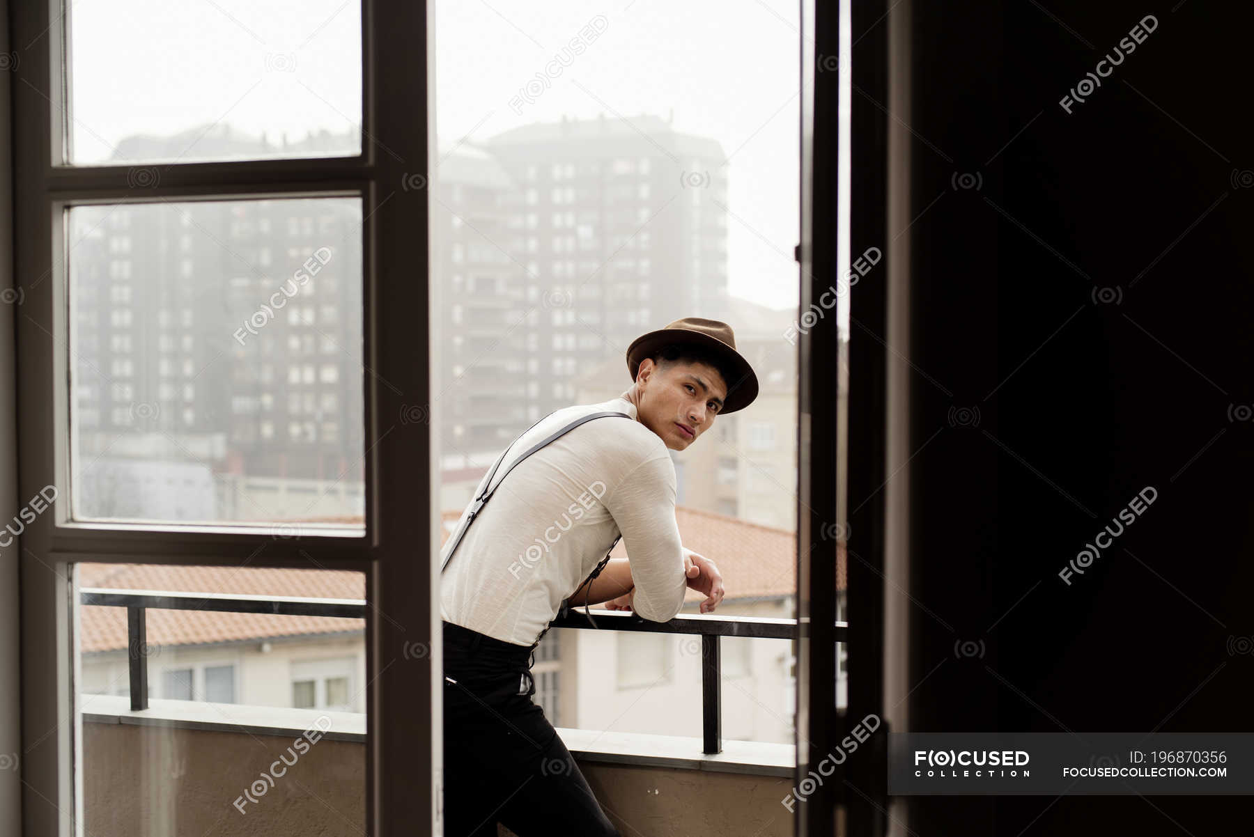 Handsome Man Leaning On Balcony Handrail And Looking Over Shoulder At Camera Domestic Ethnic