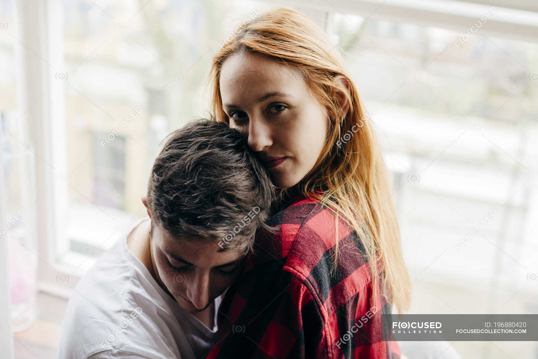 Young Blonde Girl Embracing With Boyfriend At Window And Looking At Camera — Indoors People 8307