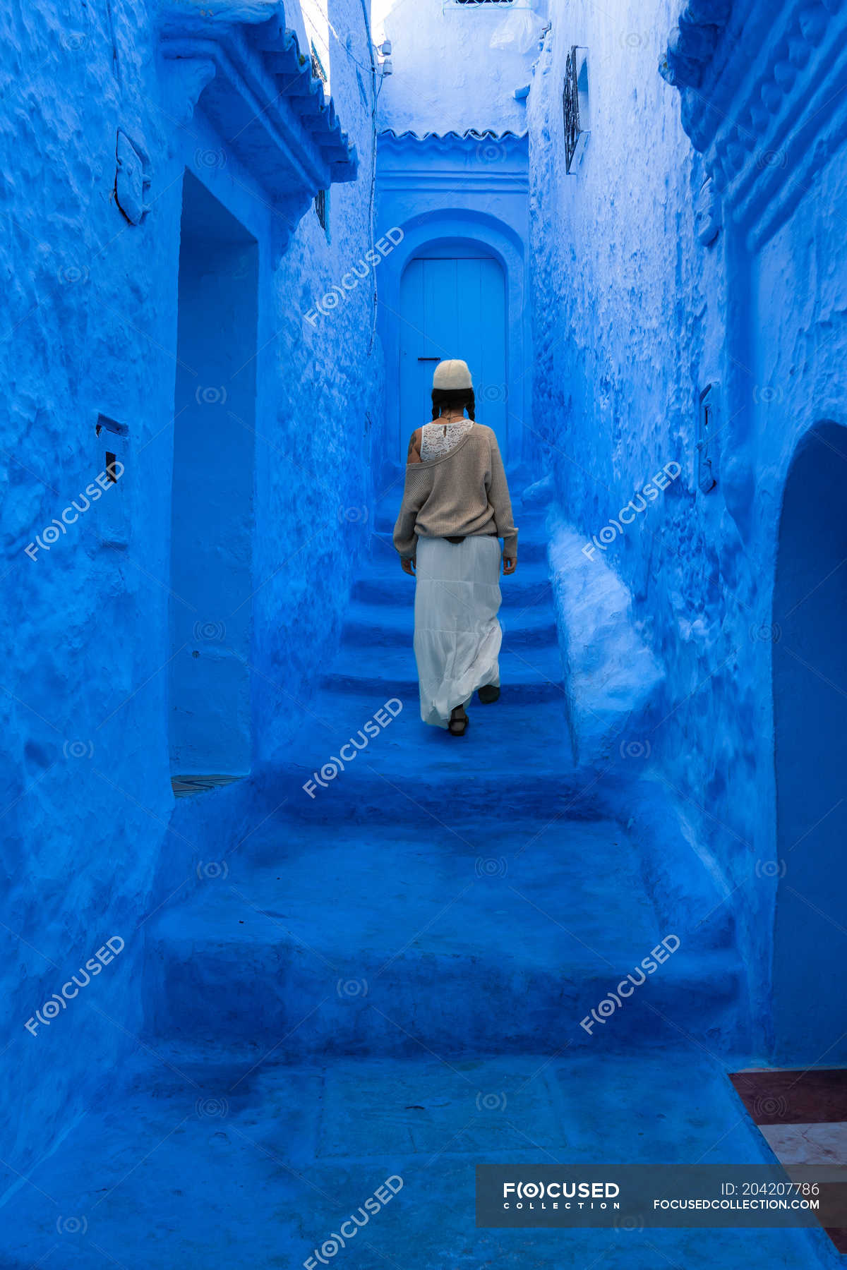 woman-walking-on-stairs-on-blue-dyed-street-morocco-bright