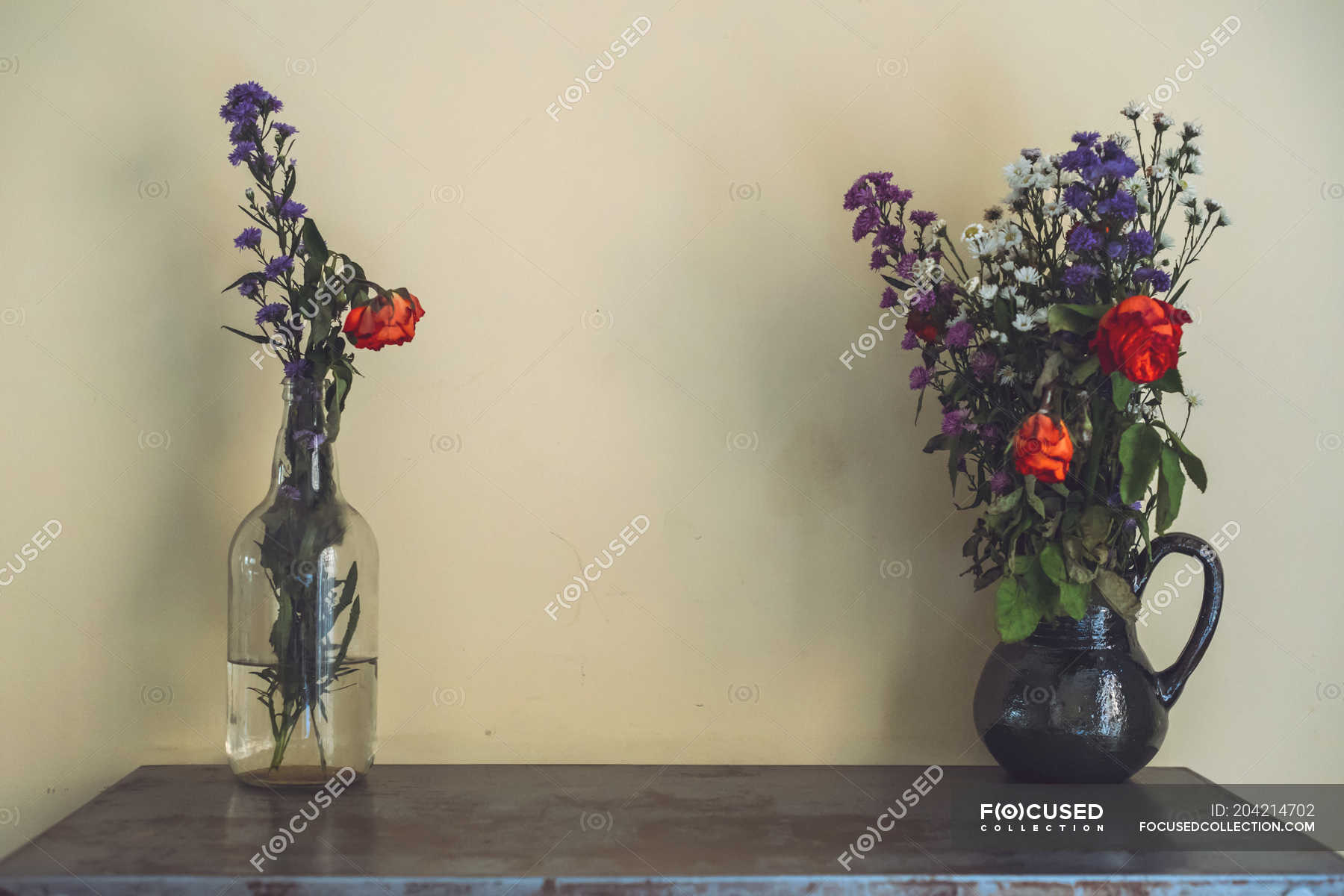 Vases With Flowers On Table In Front Of Wall Front View