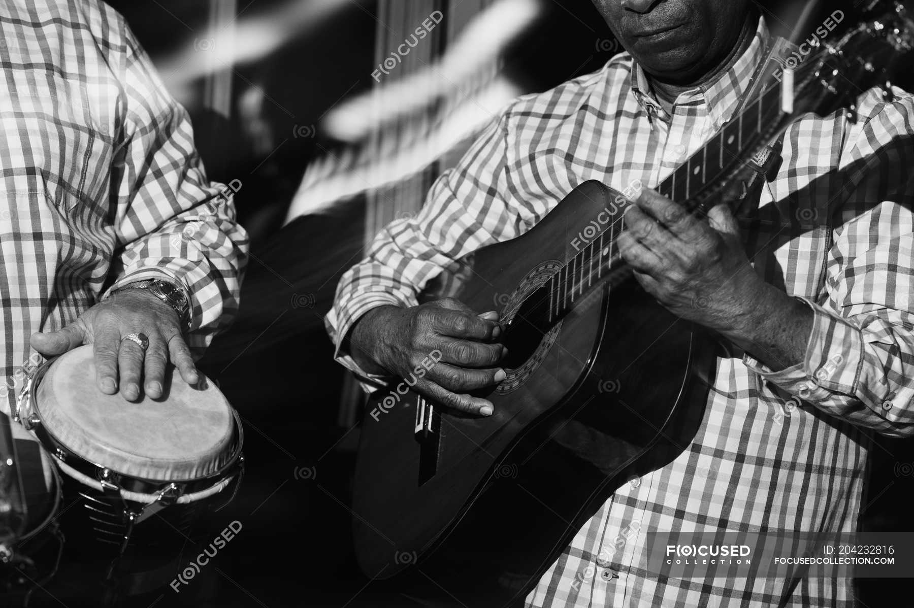 Musicians playing guitar and drums in night club, black and white shot ...
