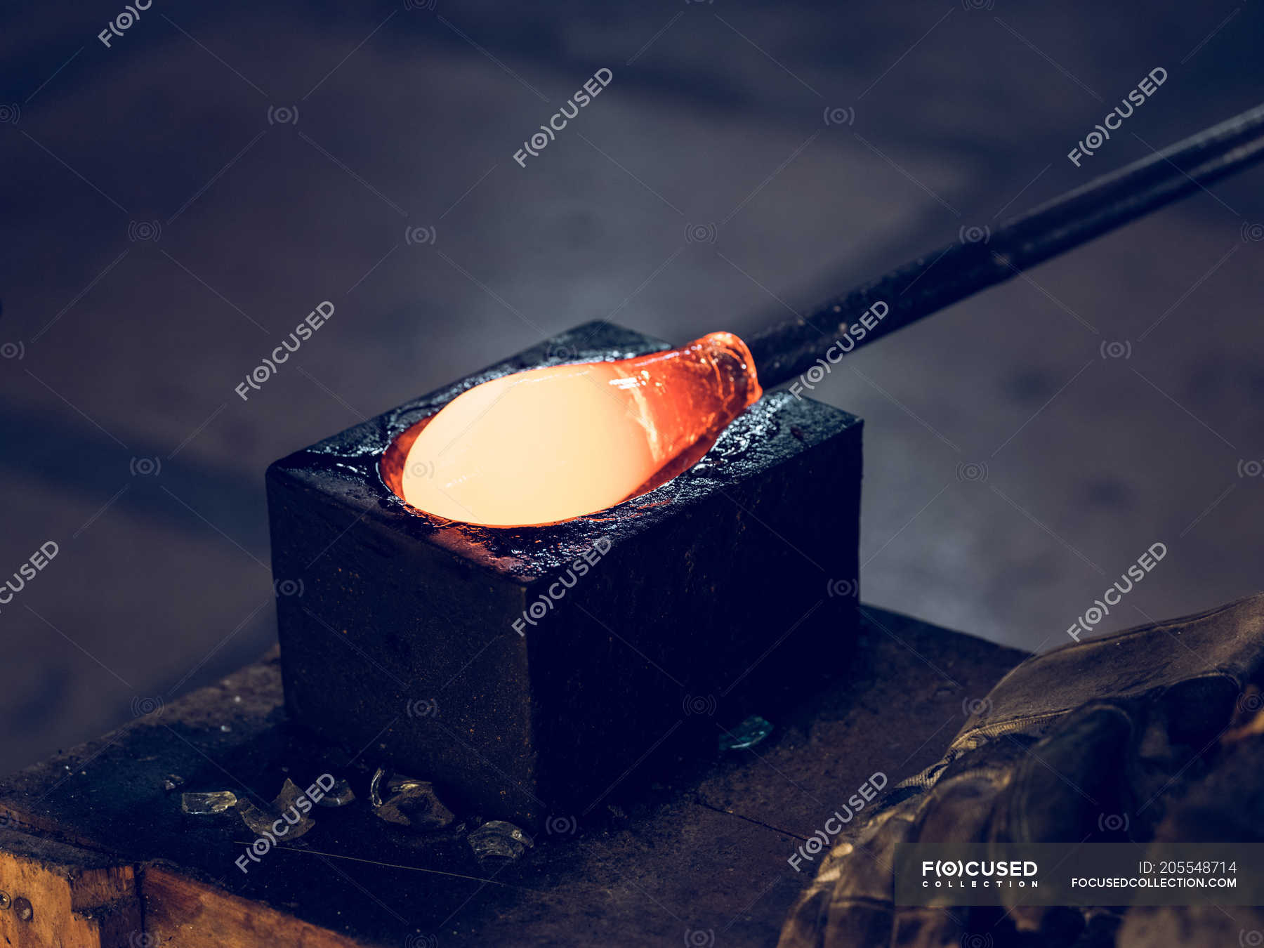 Red hot glass prepared for blowing on pipe on glassblowing factory ...