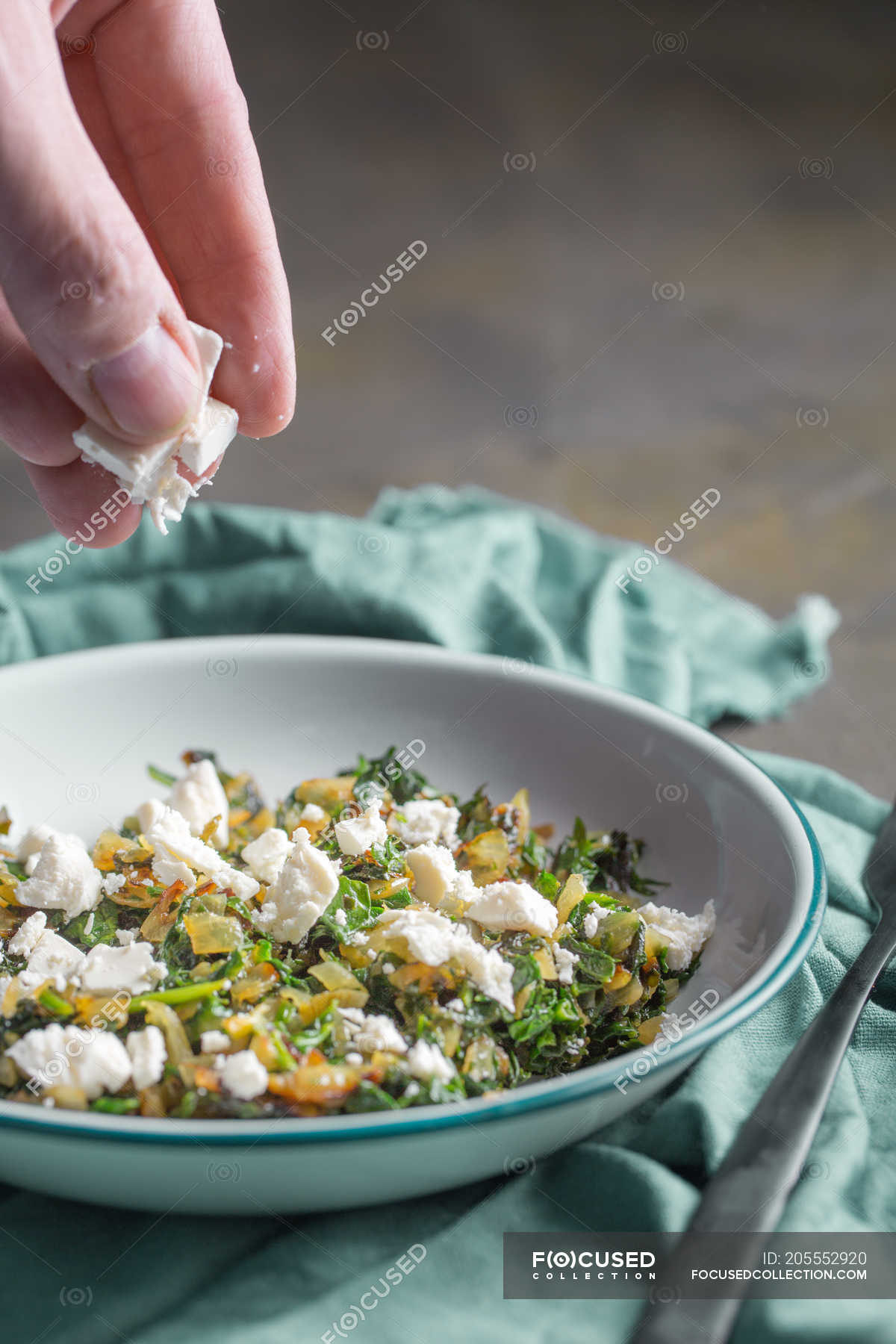 Menschliche Hand, die Feta in Füllung für traditionellen Spanakopita ...