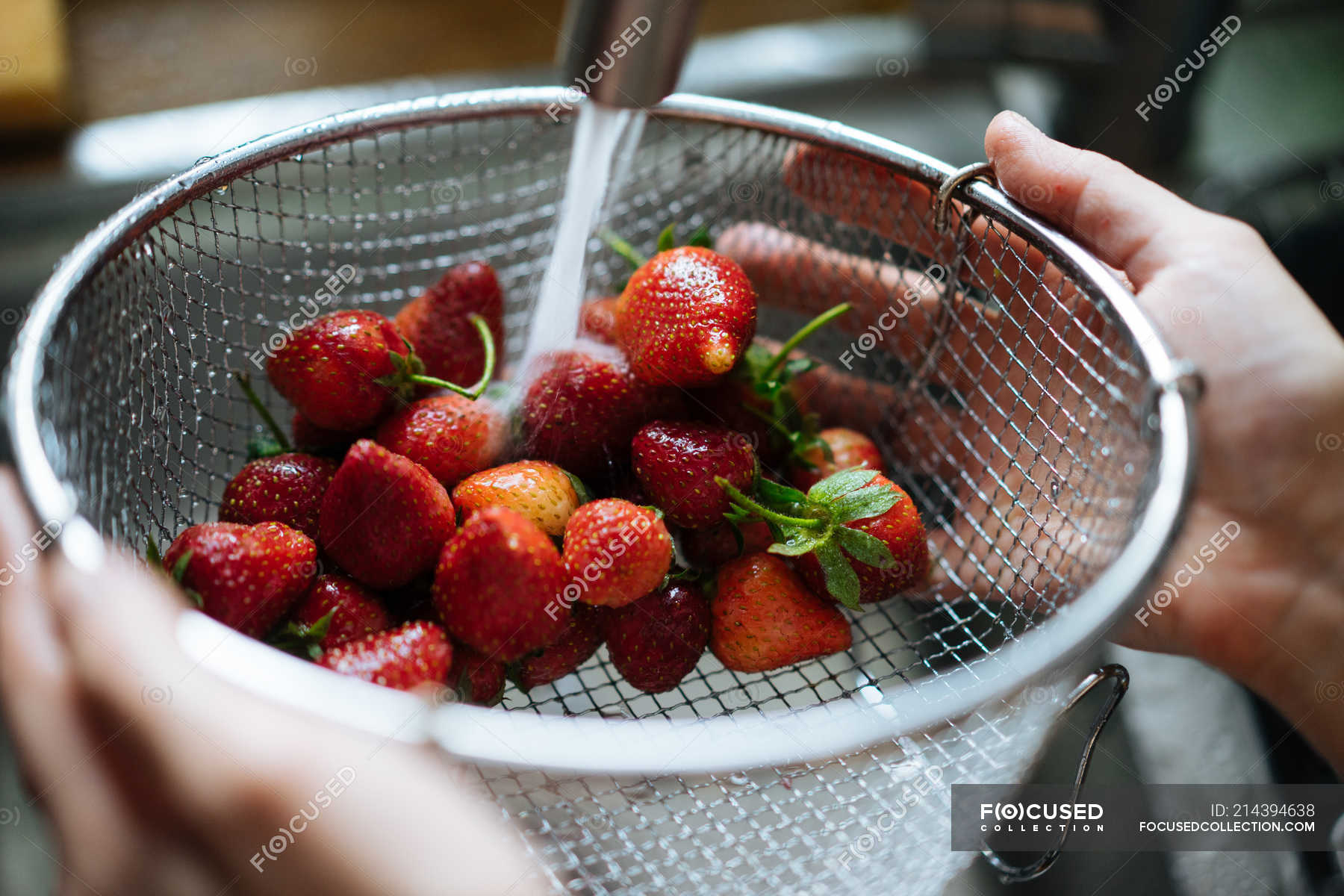 Human hands washing strawberries under sink tap — cropped image ...