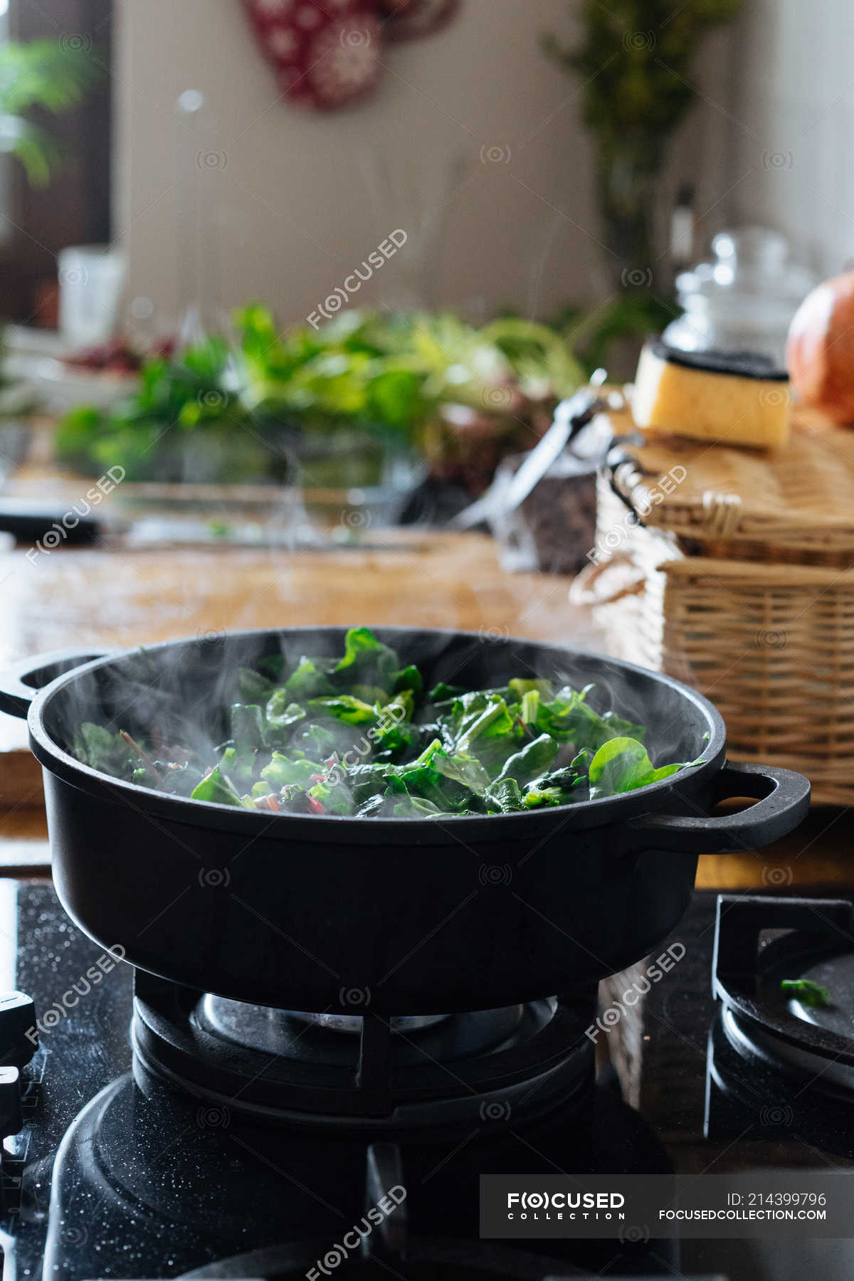 Cooking spinach leaves in pot on gas stove — healthy, indoor Stock