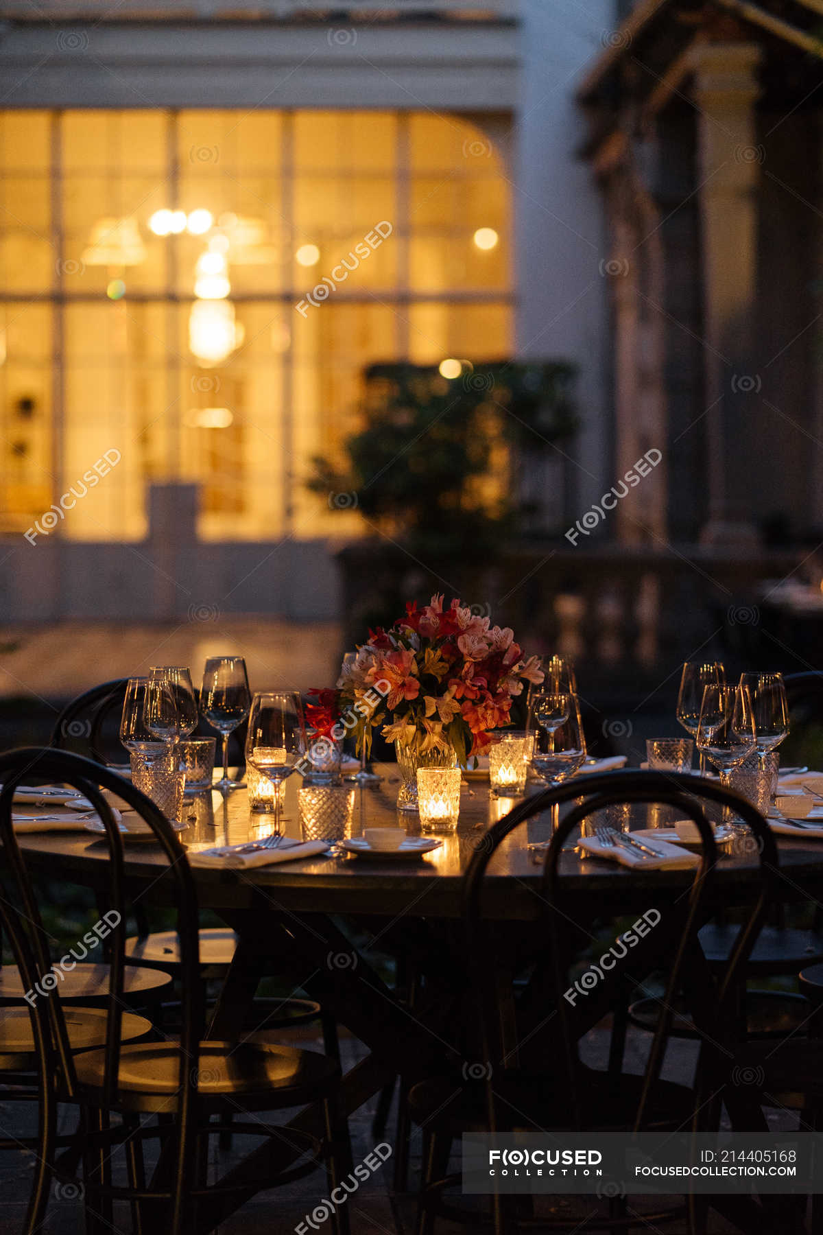 Setting Table Decorated With Candles And Flowers At Night On