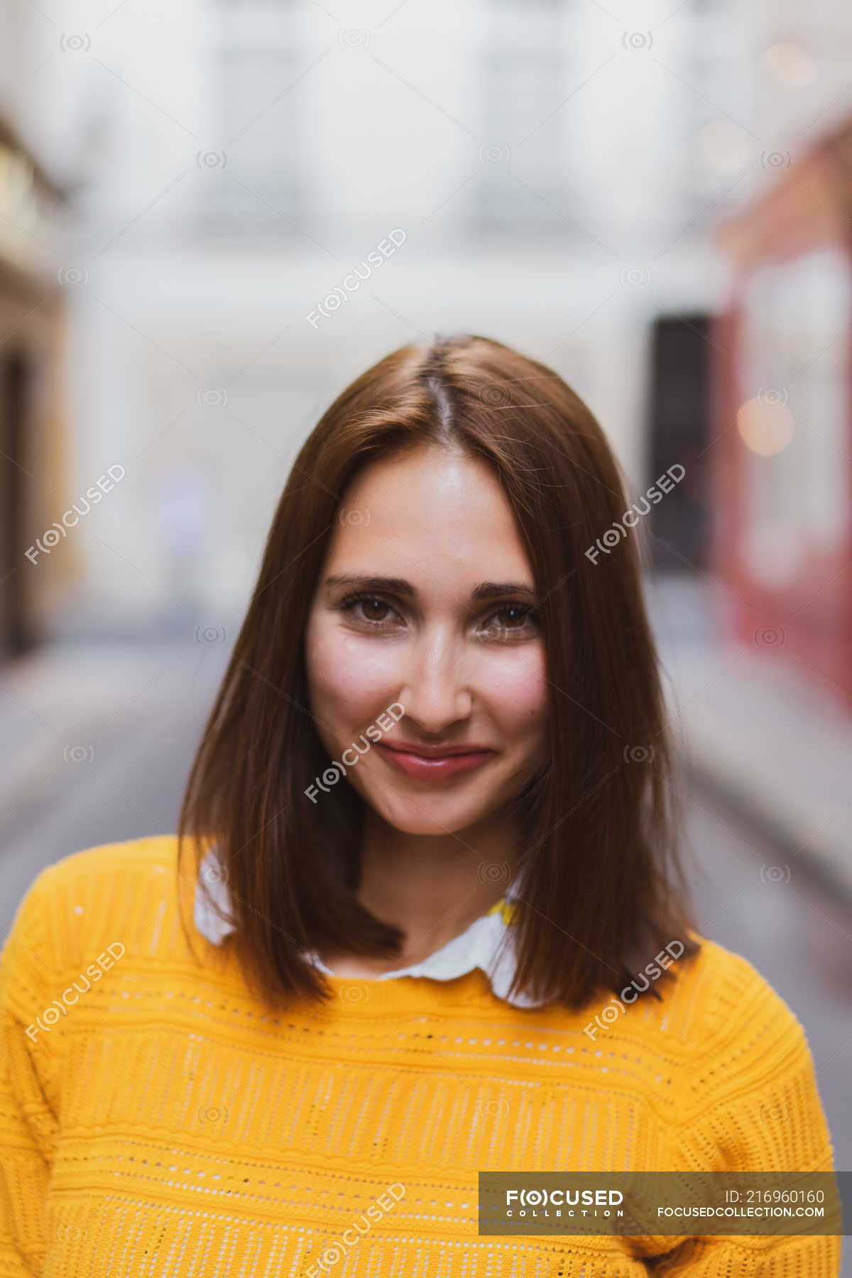 Smiling Woman In Yellow Cardigan Standing On Street And Looking At Camera Attractive Head And