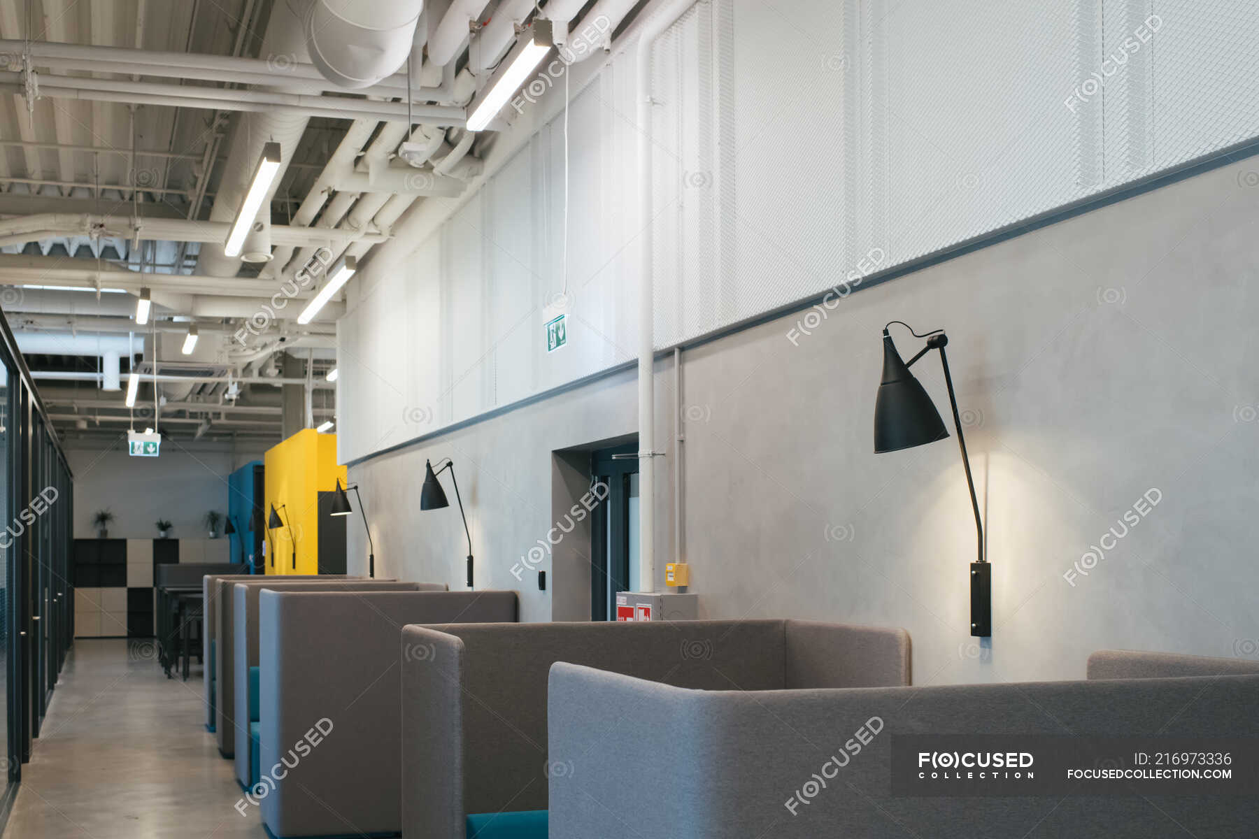 Grey interior of office cafeteria with empty tables and sofas with high  backs and lamps hanging on walls — urban, room - Stock Photo | #216973336