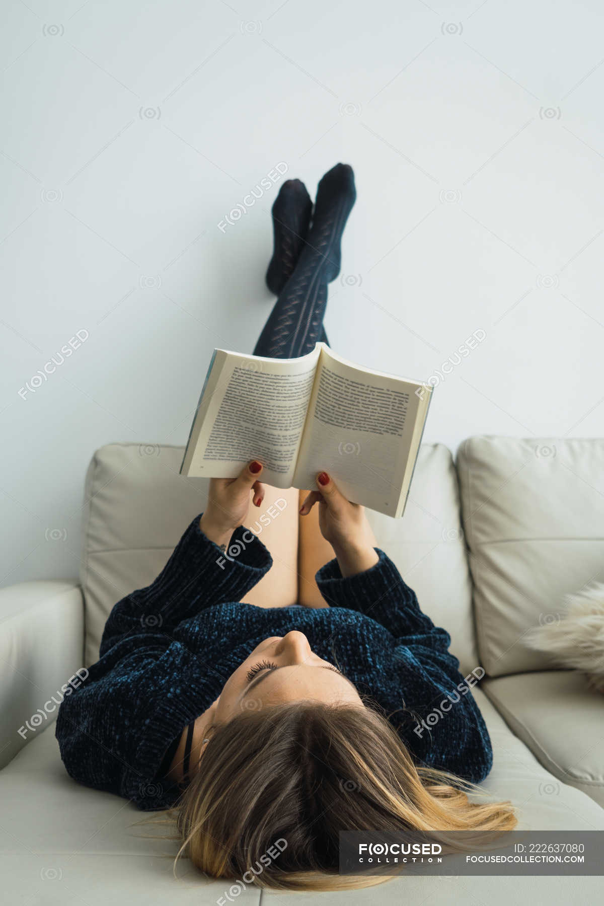 Blonde girl absorbed with reading on coach at home — content, tranquil -  Stock Photo | #222637080