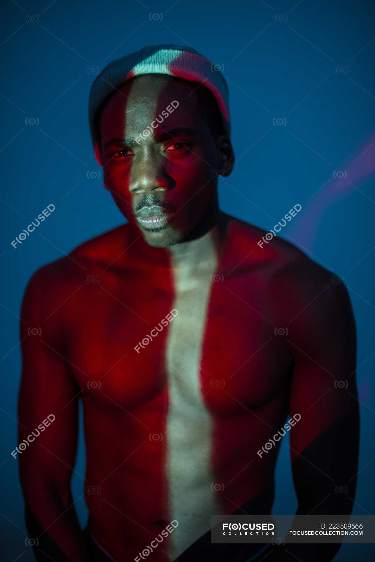 Emotionless ethnic man standing with light line on body and looking at ...