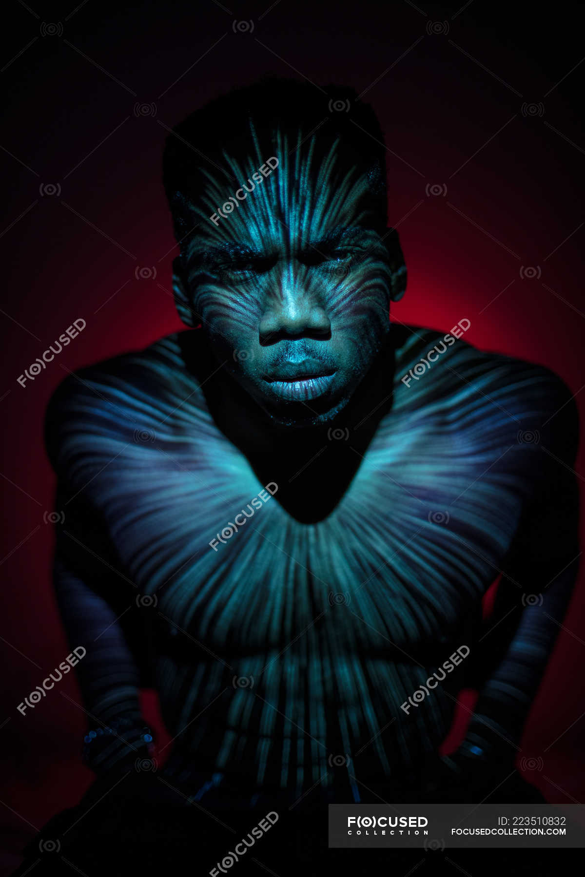 Emotionless ethnic man standing with light lines on body and looking at ...