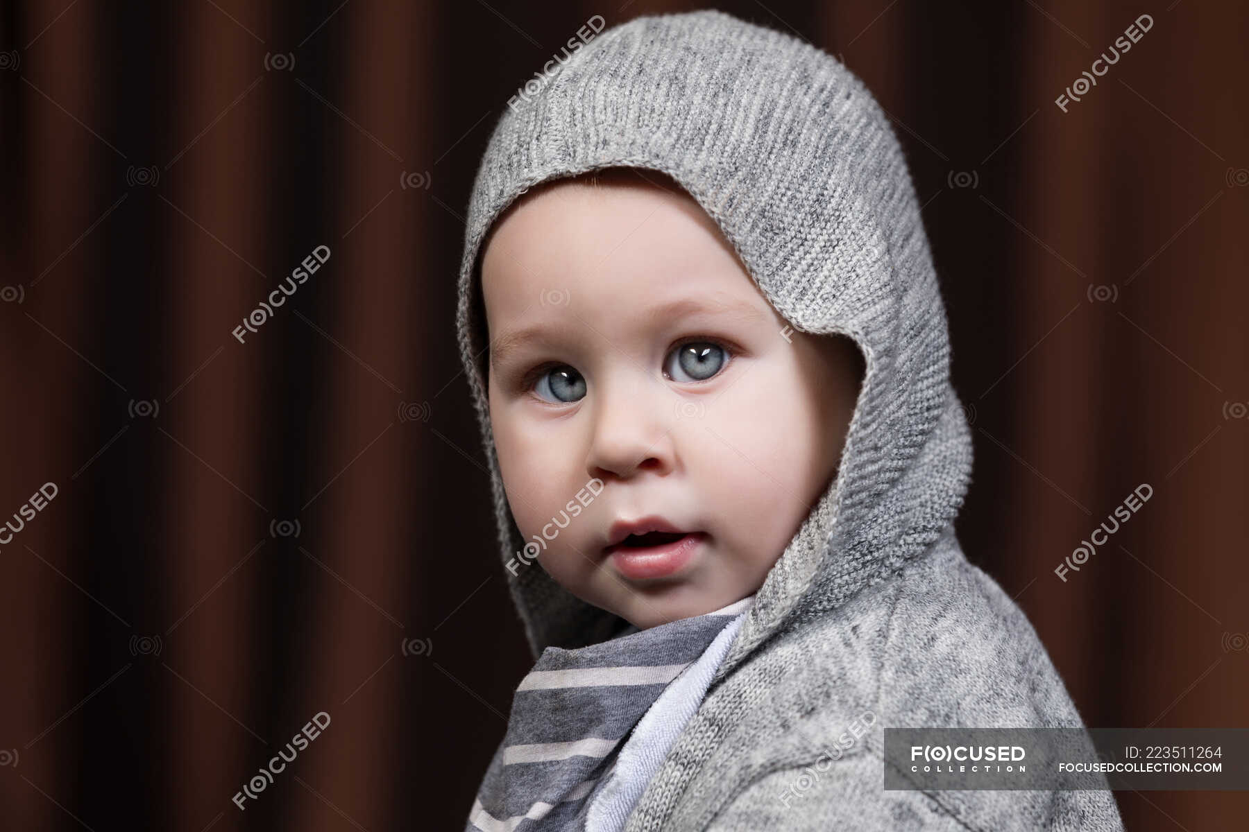 Portrait of adorable little toddler looking at camera on gray ...